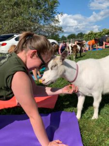 girl snuggling a goat during goat yoga