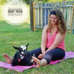 Woman sitting on a yoga mat with a goat.