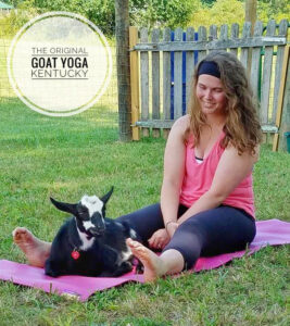 Woman sitting on a yoga mat with a goat.